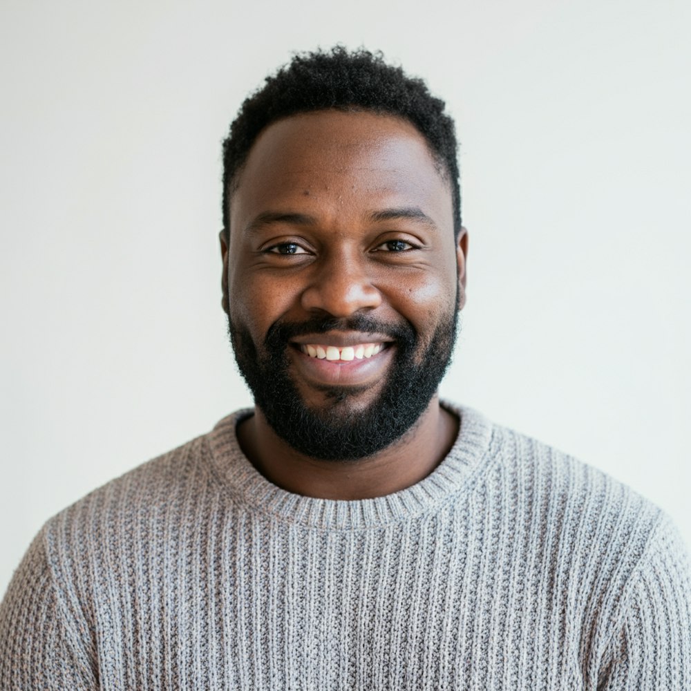 Portrait of Daniel Okafor, a smiling man with a beard in a grey knit sweater