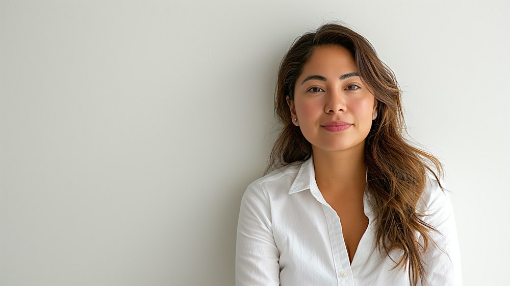 Portrait of Sofia Marín, a woman with long brown hair in a white shirt against a light wall
